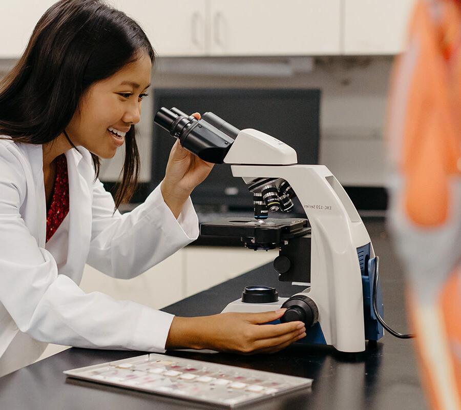 Student looks into a microscope in a laboratory session.