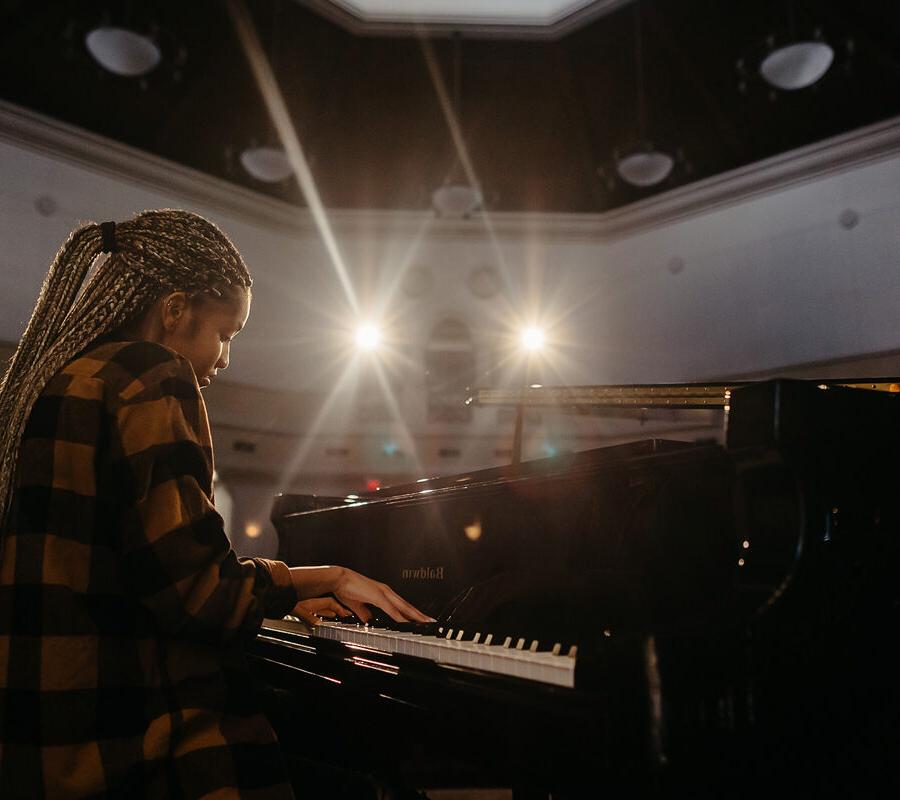 Music student plays the piano in an auditorium.