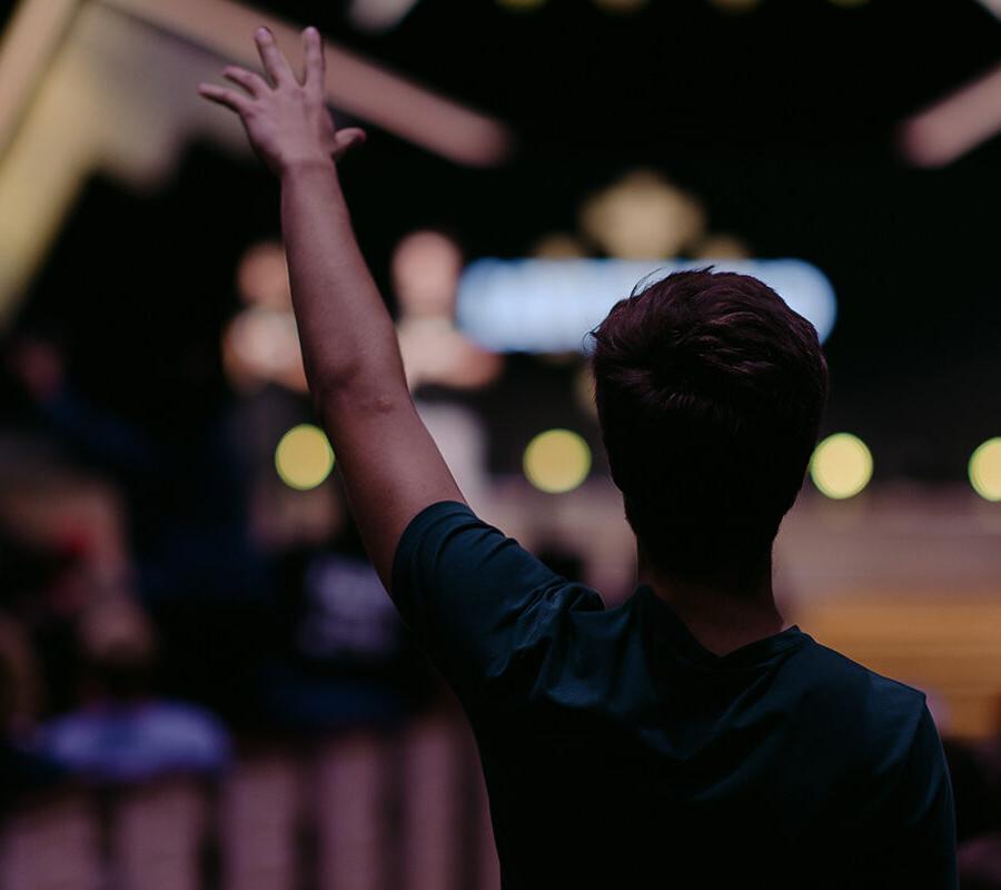 Christian community development minor student raises hand in chapel.